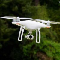 white-drone-flying-with-trees-in-background