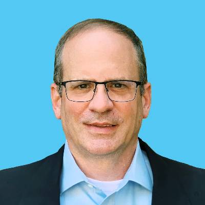 Friendly man smiling in dark blazer with blue shirt and wearing glasses